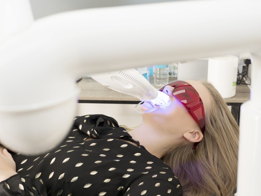 Young woman in dentist chair, having teeth whitened